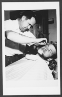 Photograph of a barber shaving a customer, Boulder City, Nevada, circa 1947-1950