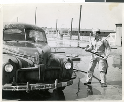 Photograph of Sherwin Garside washing a car, Camp Phillips, Kansas, circa 1940s.