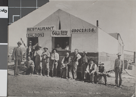 Photograph of men outside of a building serving as multiple businesses, Goldfield, Nevada, October 11, 1908