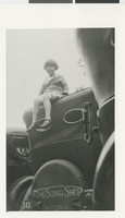 Photograph of Ruth Andre sitting on the roof of her father's car, 1920s