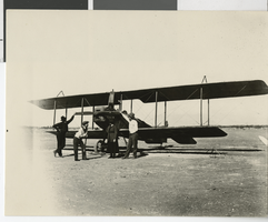 Photograph of four people in front of an airplane, 1920s