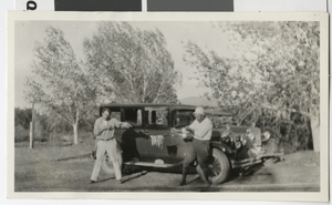 Photograph of two men holding fish in front of an automobile, 1920s