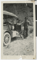 Photograph of man standing by an automobile, 1910s