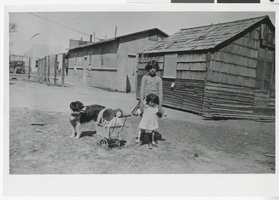Photograph of two young girls playing near a row of buildings, Las Vegas (Nev.), 1929