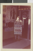Photograph of a woman holding a sign advertising "Pocketful of Miracles" outside of the Fremont Theatre, Las Vegas (Nev.), 1961