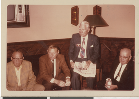 Photograph of men in different colored suits on a couch, 1970s-early 1980s