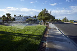 Sprinklers water common area grass on West Sahara Avenue in The Lakes development, Las Vegas, Nevada: digital photograph