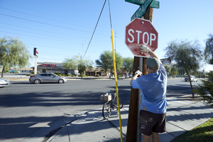 Man cleans graffiti off stop sign on Kendale Street and East Sahara Avenue, looking north, Las Vegas, Nevada: digital photograph