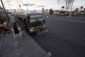 Bus passengers load onto bus at East Sahara Avenue at Maryland Parkway looking west at dusk, Las Vegas, Nevada: digital photograph