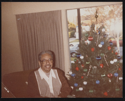 Nelson Skyes posing by a Christmas tree: photographic print