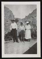 Mr. Mariger, Ralph, and Mrs. Mariger standing in front of desert landscape (identified from left to right): photographic rint