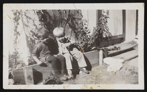 Two boys including Hazel Denton's son, Ralph Denton, sitting on edge of garden in front of a house: photographic print
