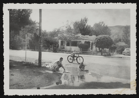 Four boys playing in puddle of water at street corner in Caliente, Nevada: photographic print