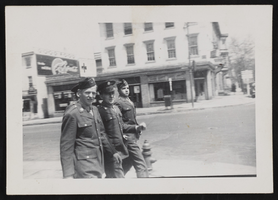 Four men in military uniforms walking on city street: photographic print