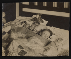 Nanelia Siegfried sleeping in bed with her dolls: photographic print