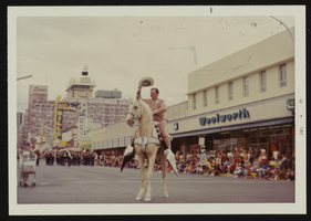 Howard Cannon on Edgewood Sunrise, Cannon's palomino horse, on Fremont Street looking northwest with the Fremont Hotel and Casino in the background: photographic print