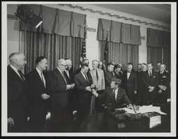 Howard Cannon, congressmen, and military leaders observe President John F. Kennedy signing documents: photographic print