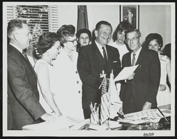 Howard Cannon signing documents with John Koontz and Dorothy Cannon next to him: photographic print
