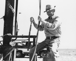 Stanley Ford operating the controls of his well-drilling equipment: photographic print