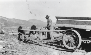 Sawing wood using the rear wheel of a truck to power the saw: photographic print