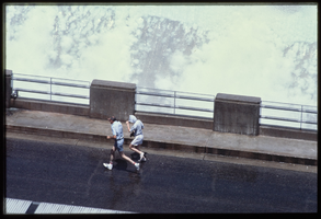 People make their way through the water spray caused by overflow water in the Arizona spillway, looking west at Hoover Dam, Arizona: photographic slide