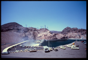 Recreational vehicles and automobiles sit in the parking lot as seen from above the Arizona spillway, looking south at Hoover Dam, Arizona: photographic slide