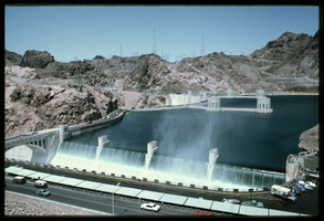 Water crashes over the Arizona spillway from a filled Lake Mead basin as seen from a lookout above the dam, looking west towards the Nevada side at Hoover Dam, Arizona: photographic slide