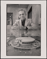 Arturo Cambiero, architect, stands looking down at a model of the Thomas &amp; Mack Center, which he designed: photographic print