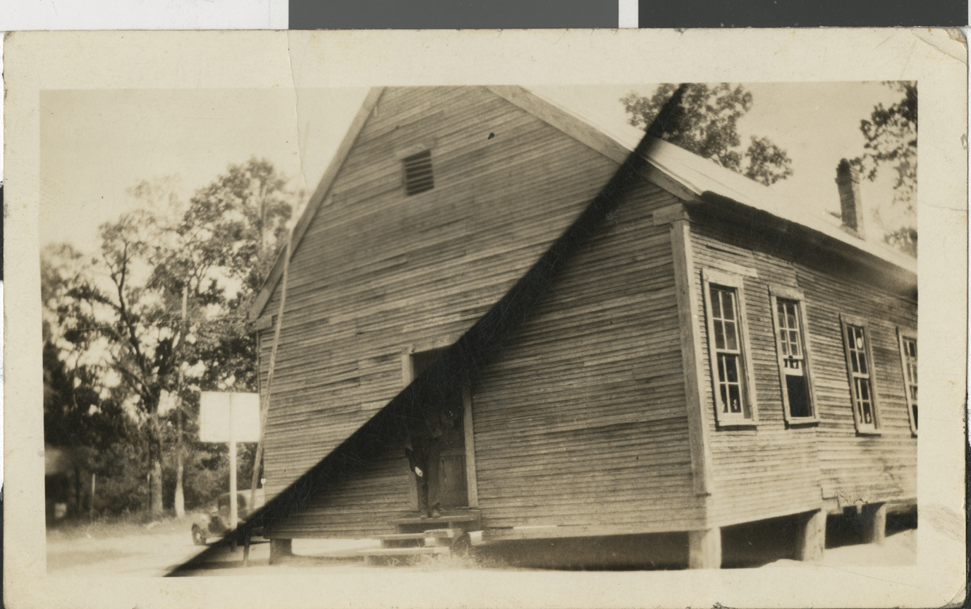 Black and white photograph of the side and facade of a wood-sided school in Karnack, Texas