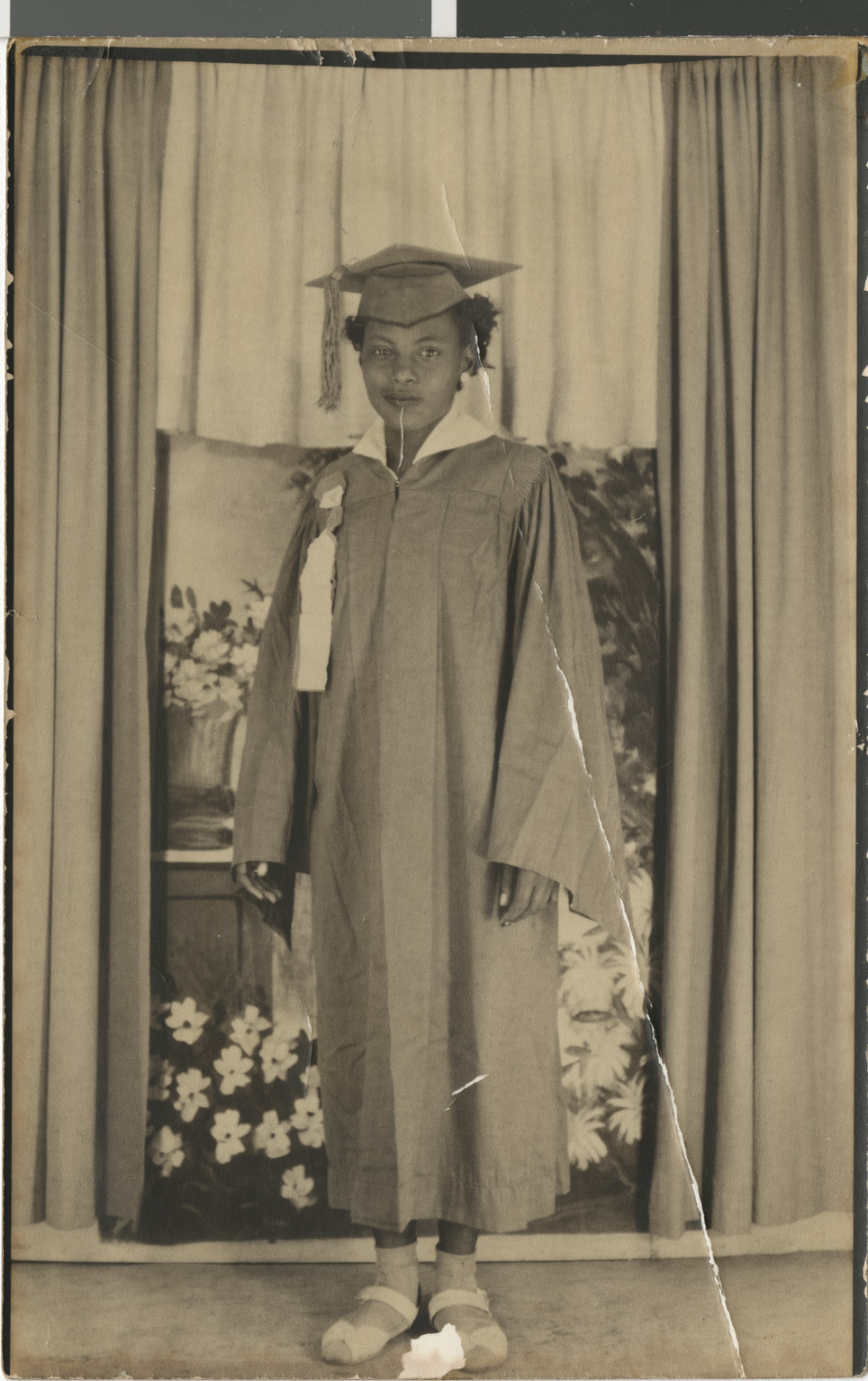 Black and white (sepia) photograph of Ruby in a graduation cap and gown, 1949