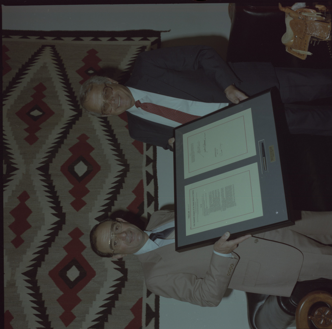 Film negative of Senator Chic Hecht and unidentified man holding Public Law 100-275 (Nevada-Florida Land Exchange Authorization Act of 1988), June 7, 1988