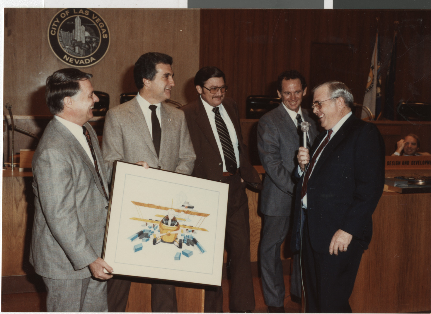 Photograph of Ron Lurie holding a framed print of a bi-plane, circa 1978