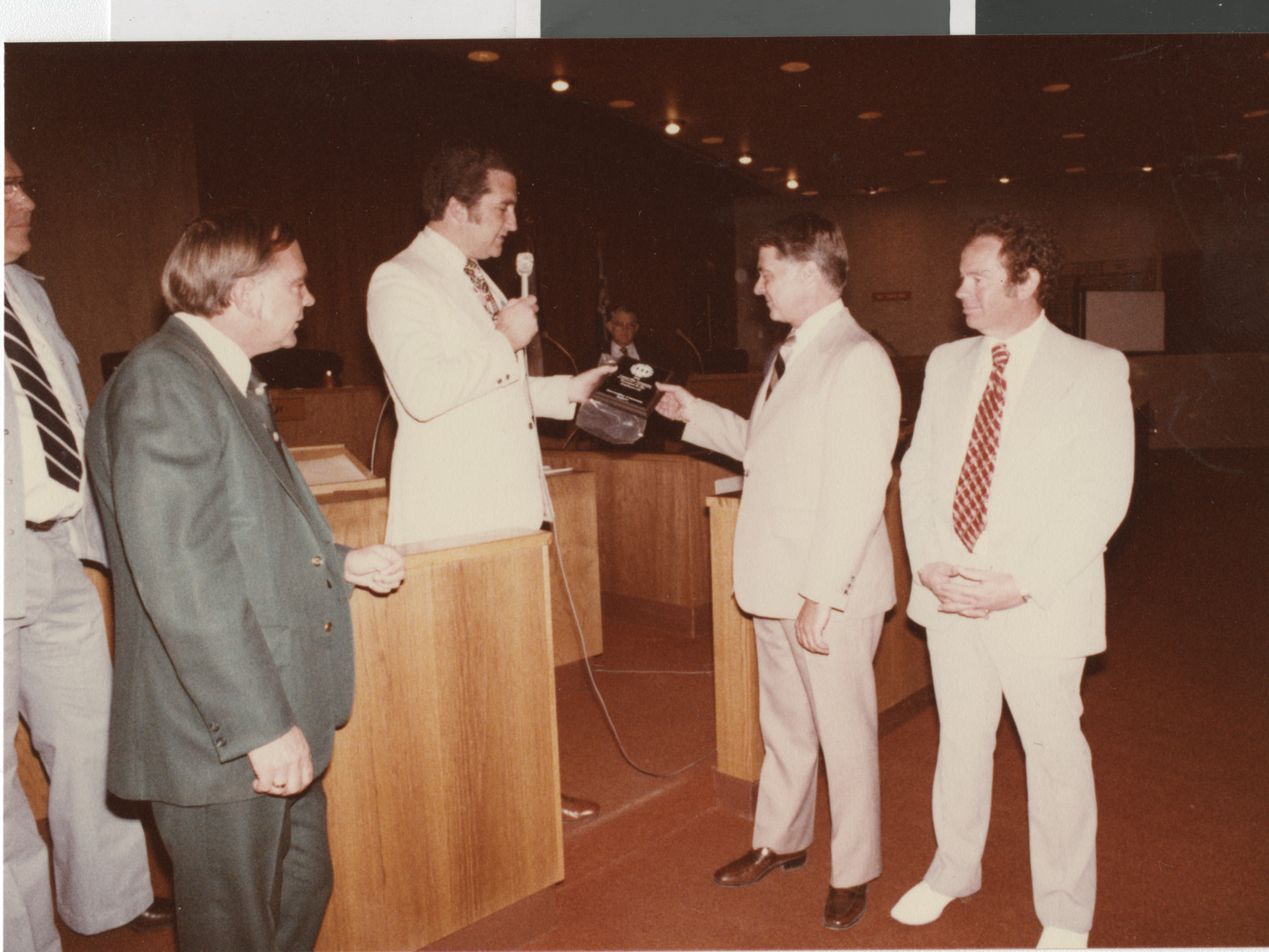 Photograph of Ron Lurie presenting a plaque in City Council chambers, circa 1978