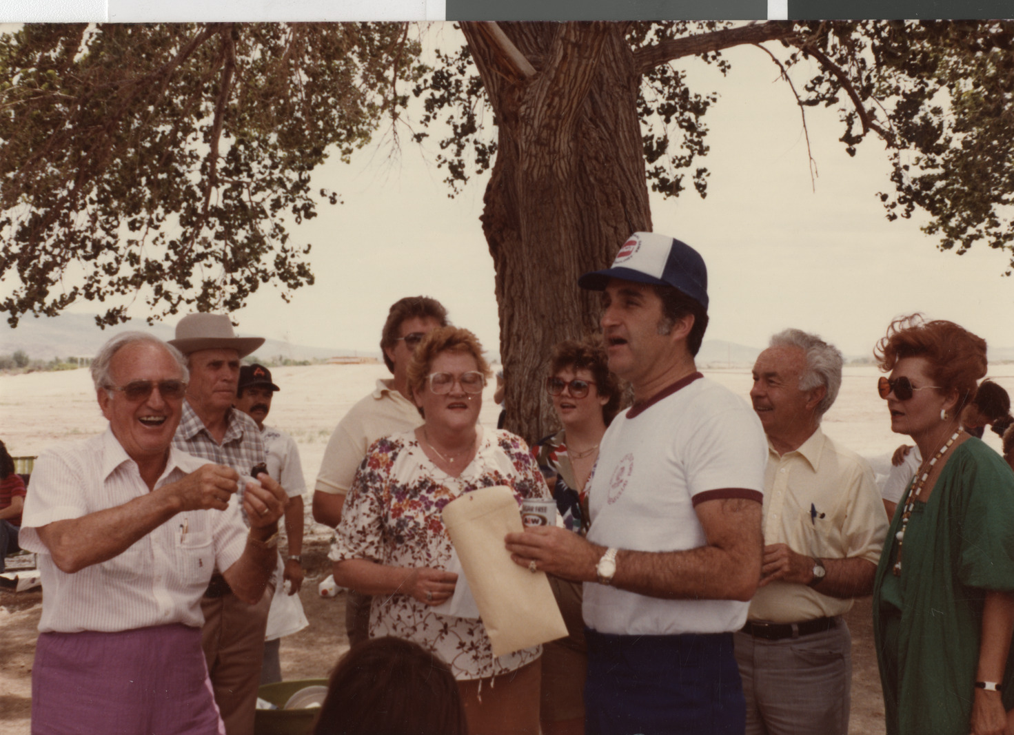 Photograph of Ron Lurie standing under a tree with a group of people