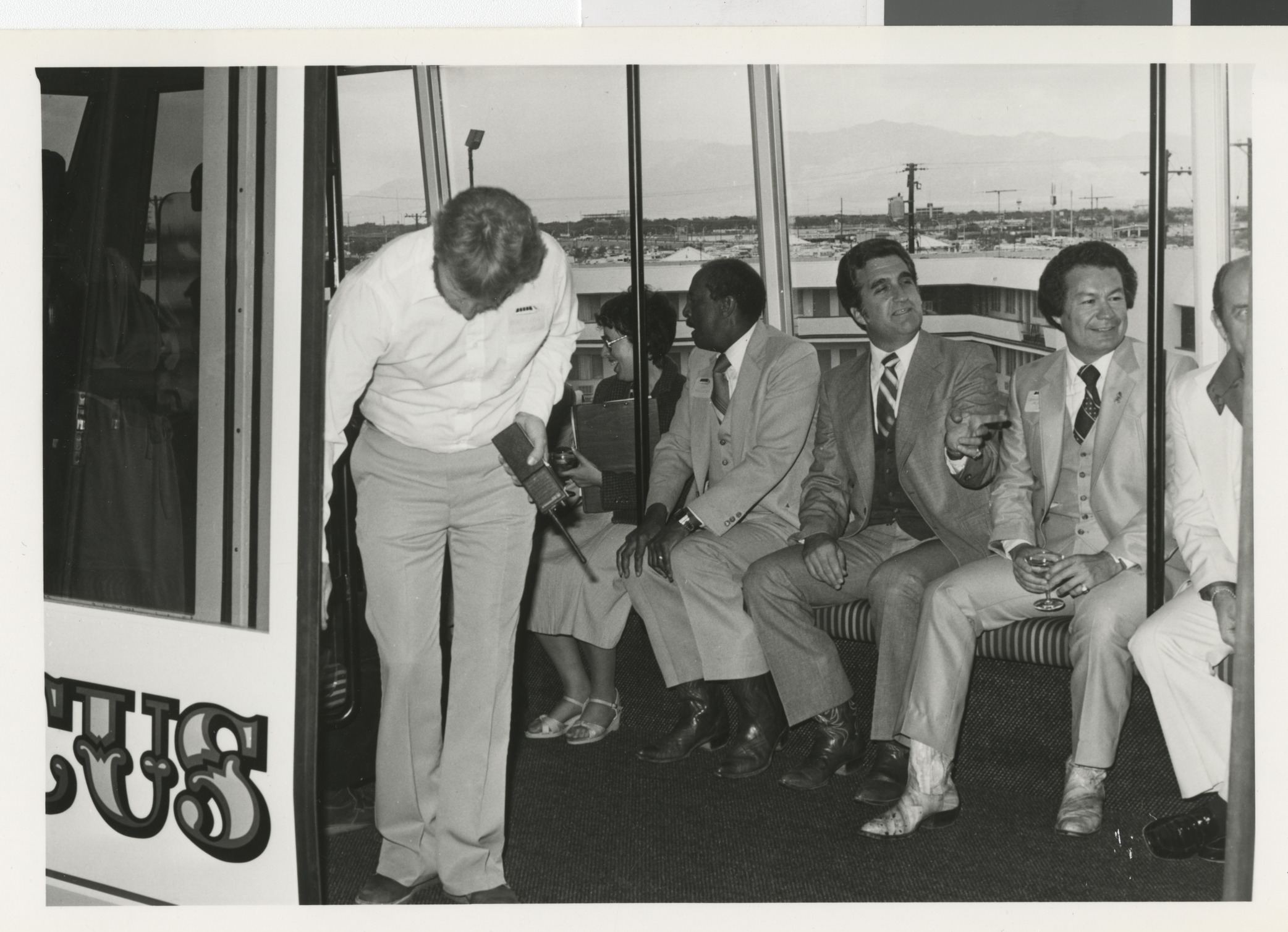 Photograph of group of men, including Commissioner Ron Lurie, on a bus, shuttle or train