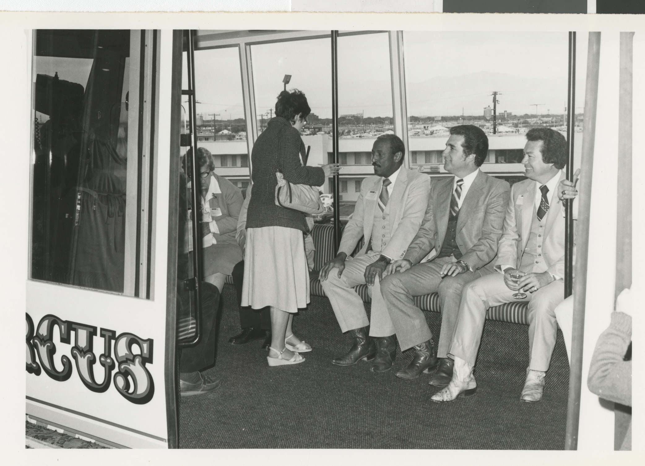 Photograph of group of men, including Commissioner Ron Lurie, on a bus, shuttle or train