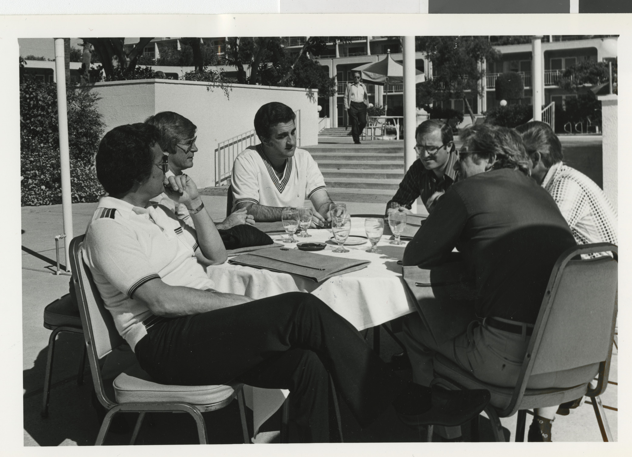 Photograph of Ron Lurie seated at a table with unidentified people outdoors