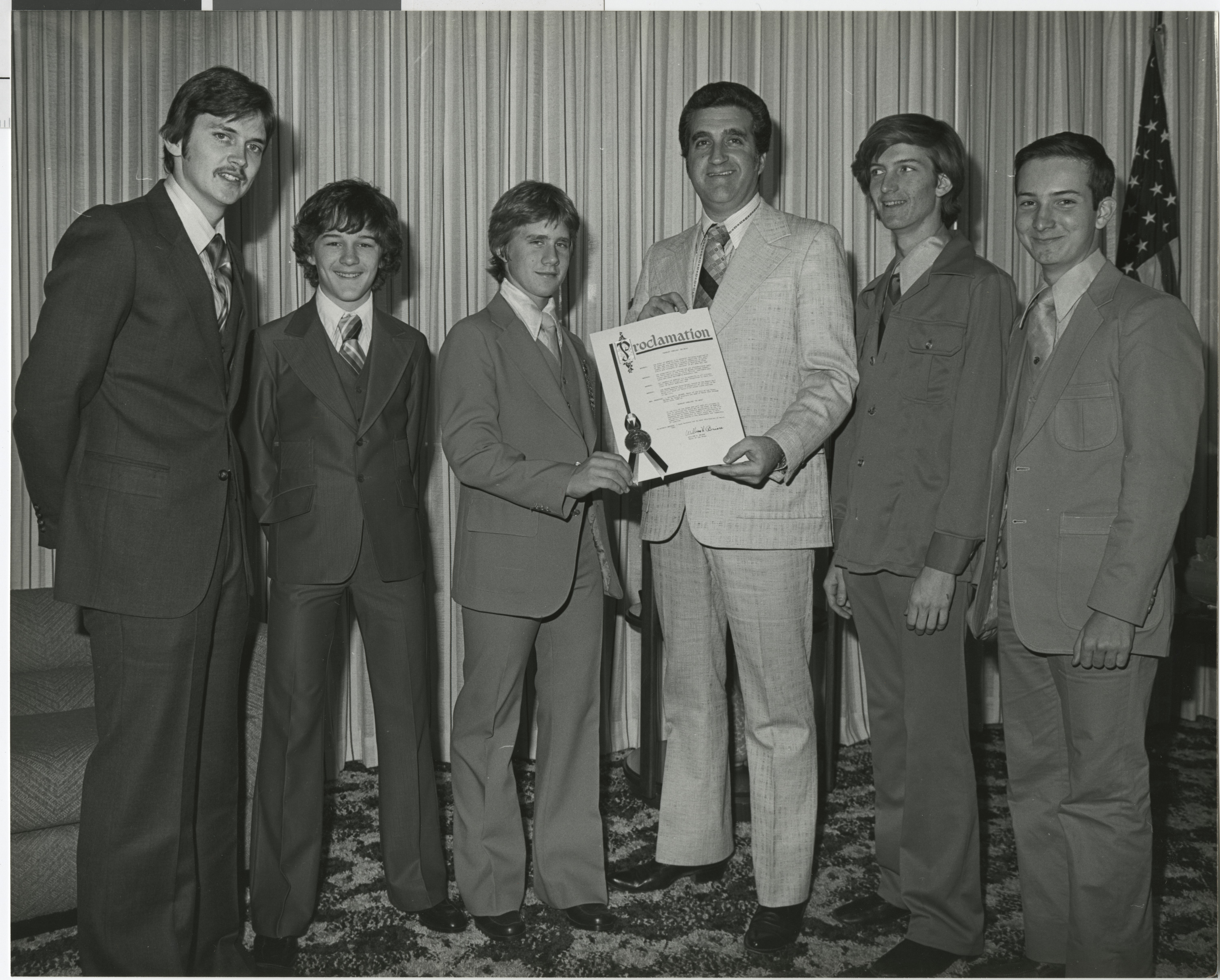 Photograph of Ron Lurie presents proclamation to a group of young men
