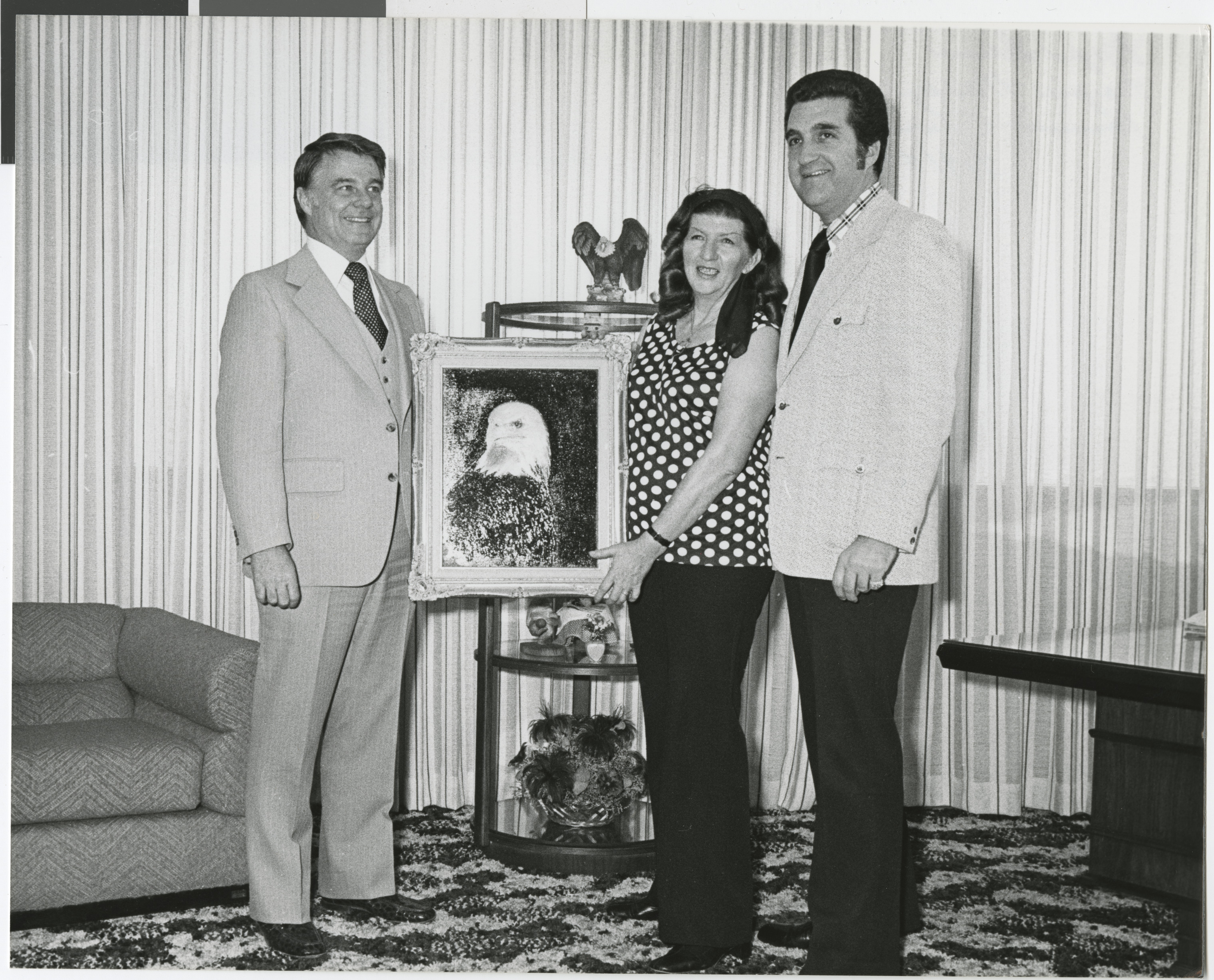 Photograph of Ron Lurie (right) with Bill Briare and Marjorie Madden with a painting of an eagle, April 4, 1977