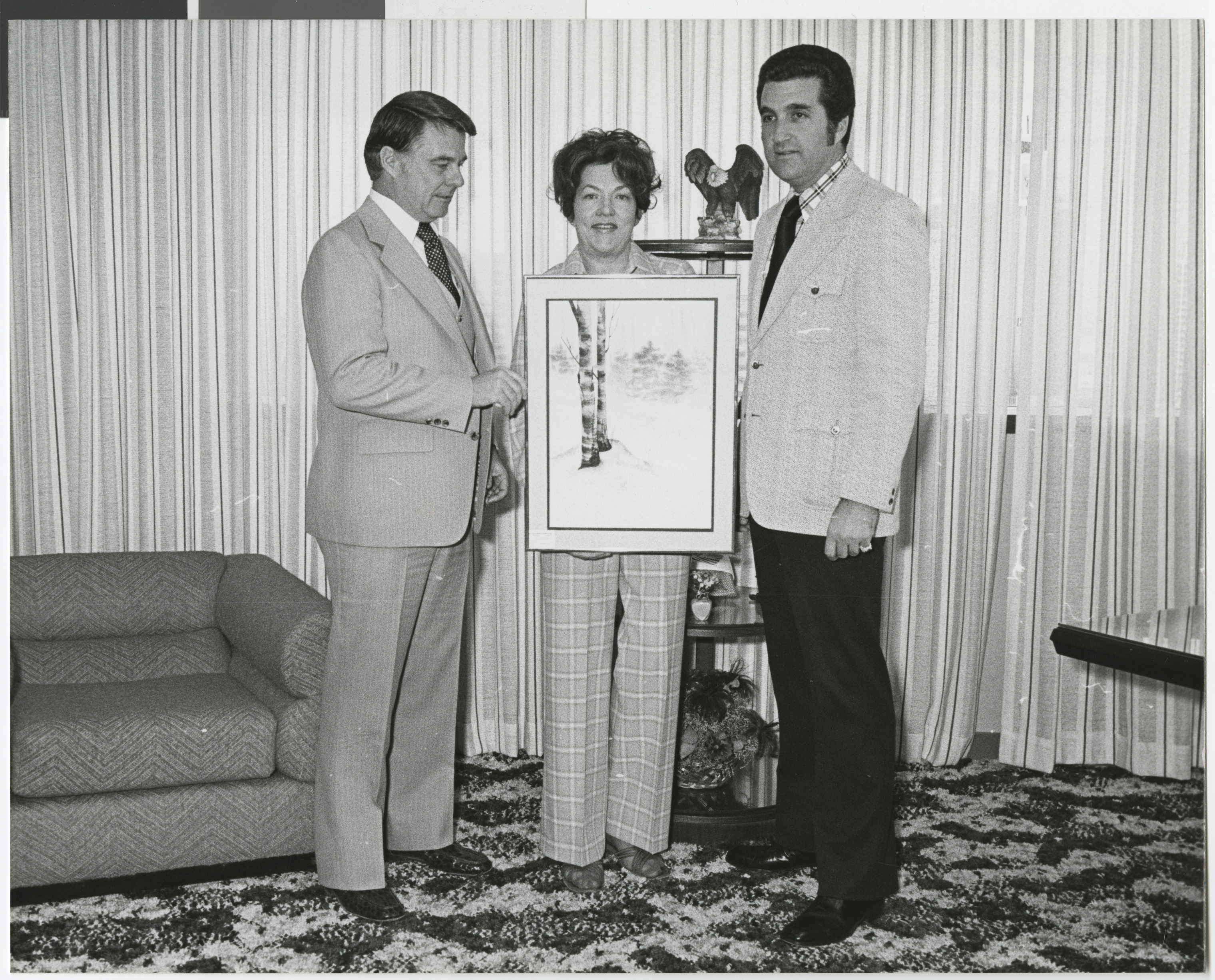 Photograph of Ron Lurie (right) with Bill Briare and M. Hendricks with a painting, April 4, 1977