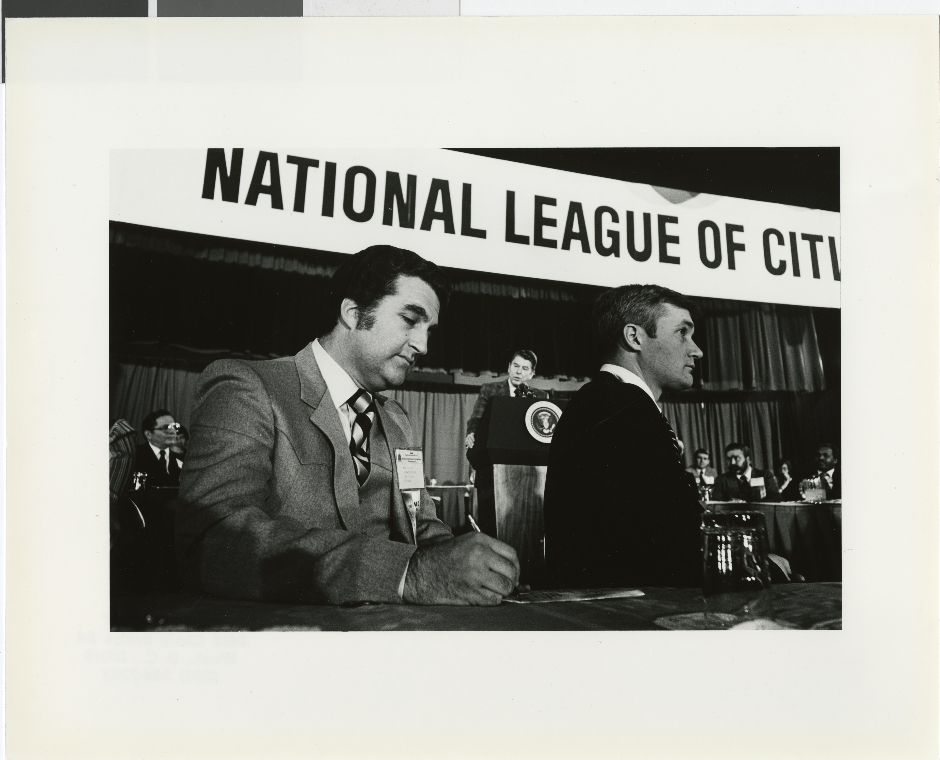 Photograph of Ron Lurie at a National League of Cities event with Ronald Reagan (at podium)