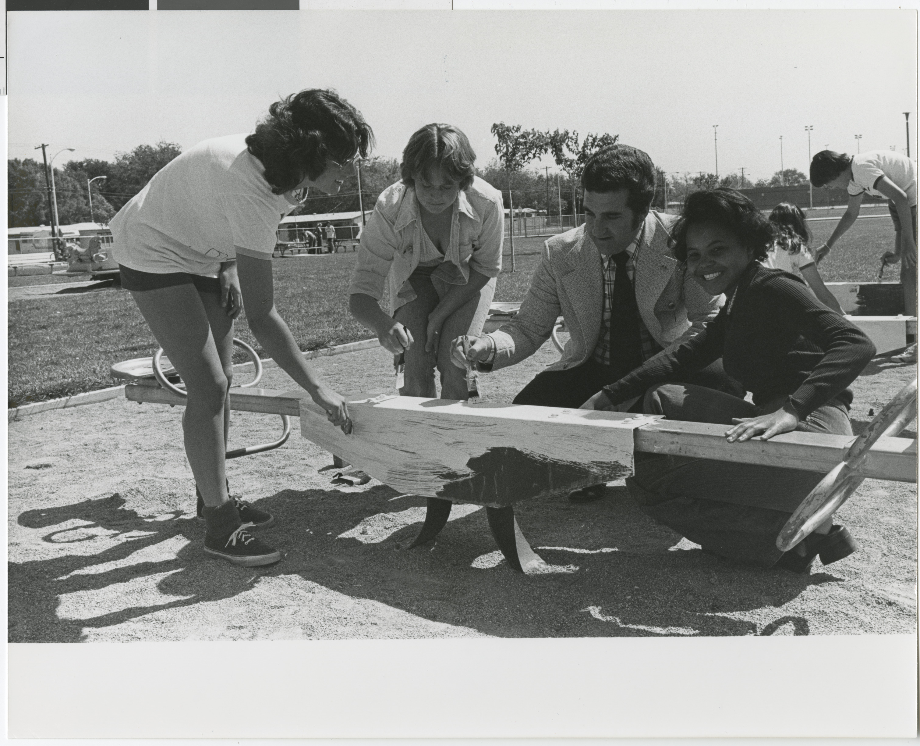 Photograph of Ron Lurie with community members painting playground equipment