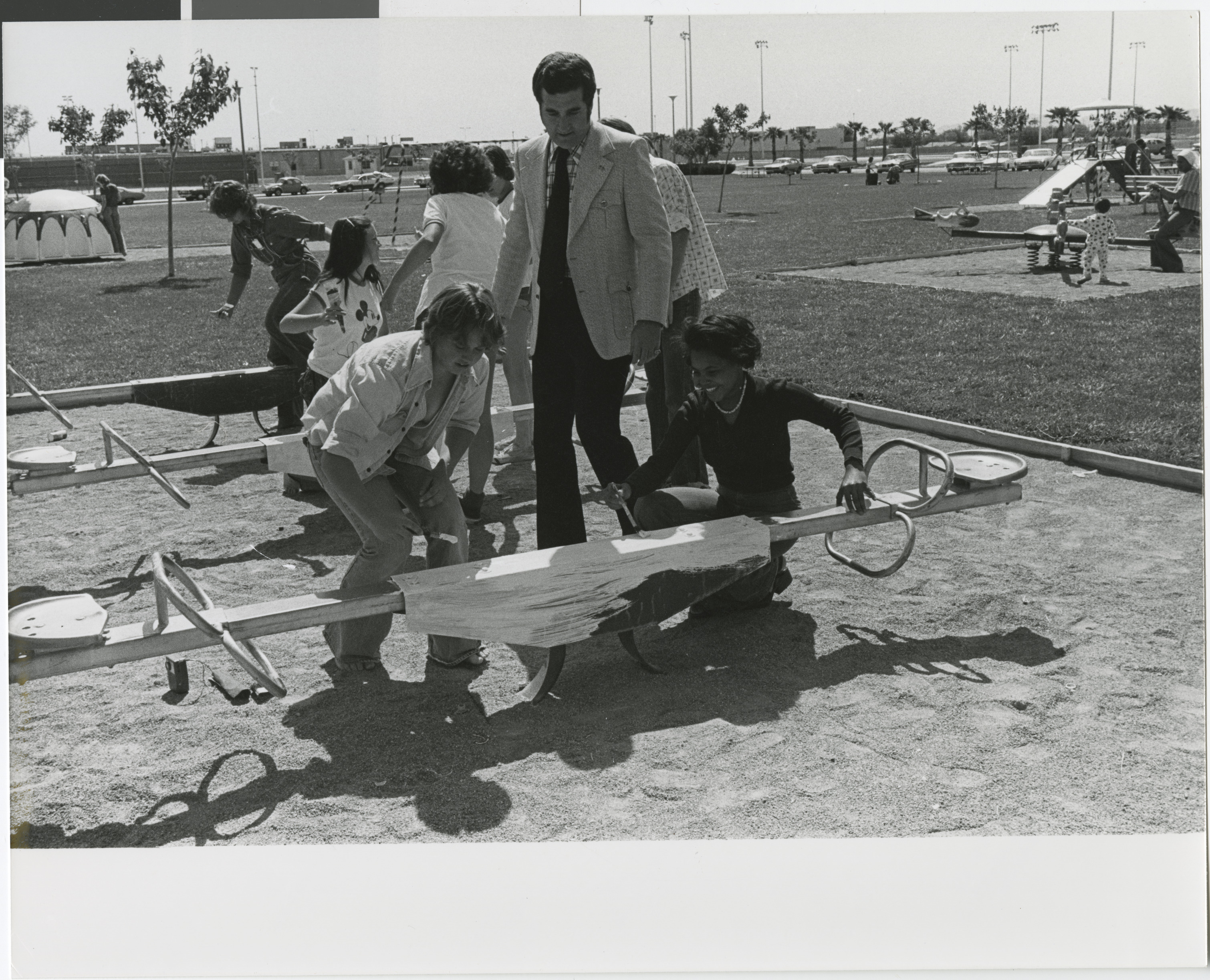 Photograph of Ron Lurie with community members painting playground equipment