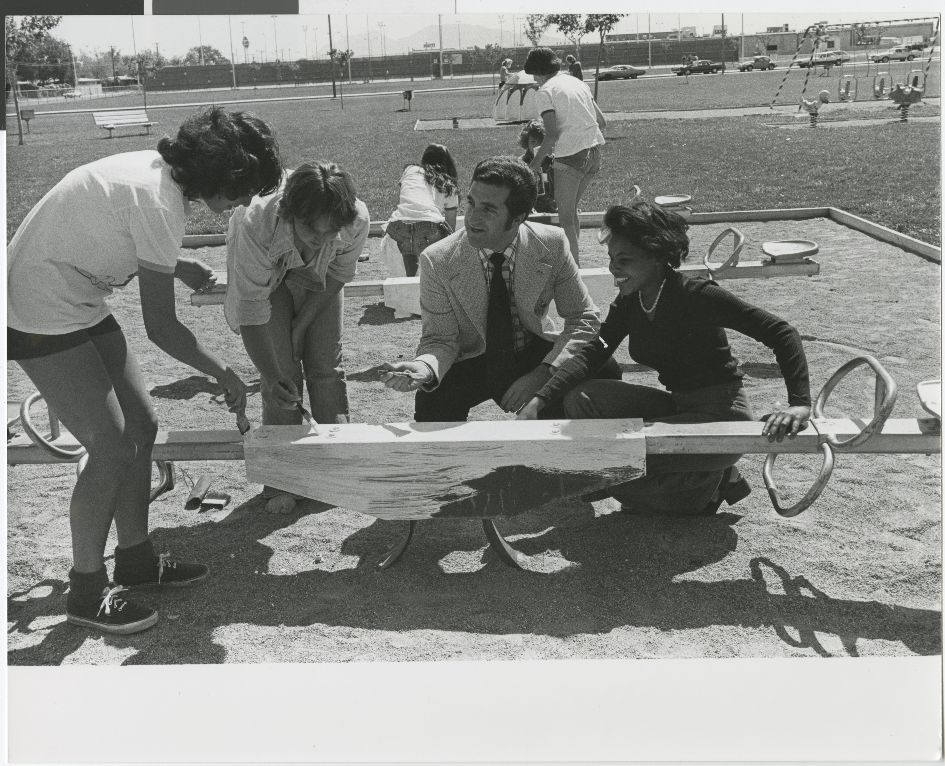 Photograph of Ron Lurie with community members painting playground equipment