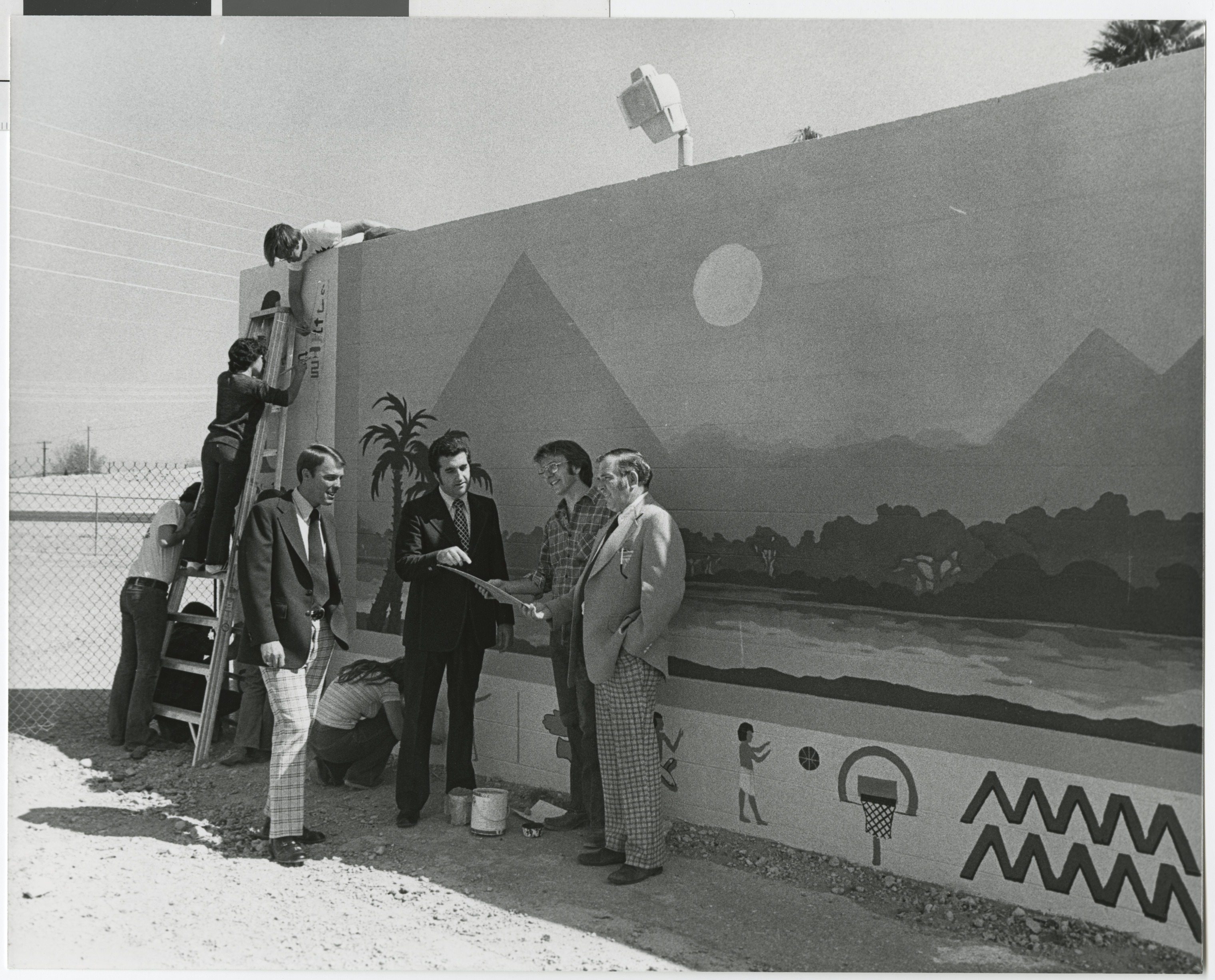 Photograph of Ron Lurie stands in front of an Egyptian-themed mural