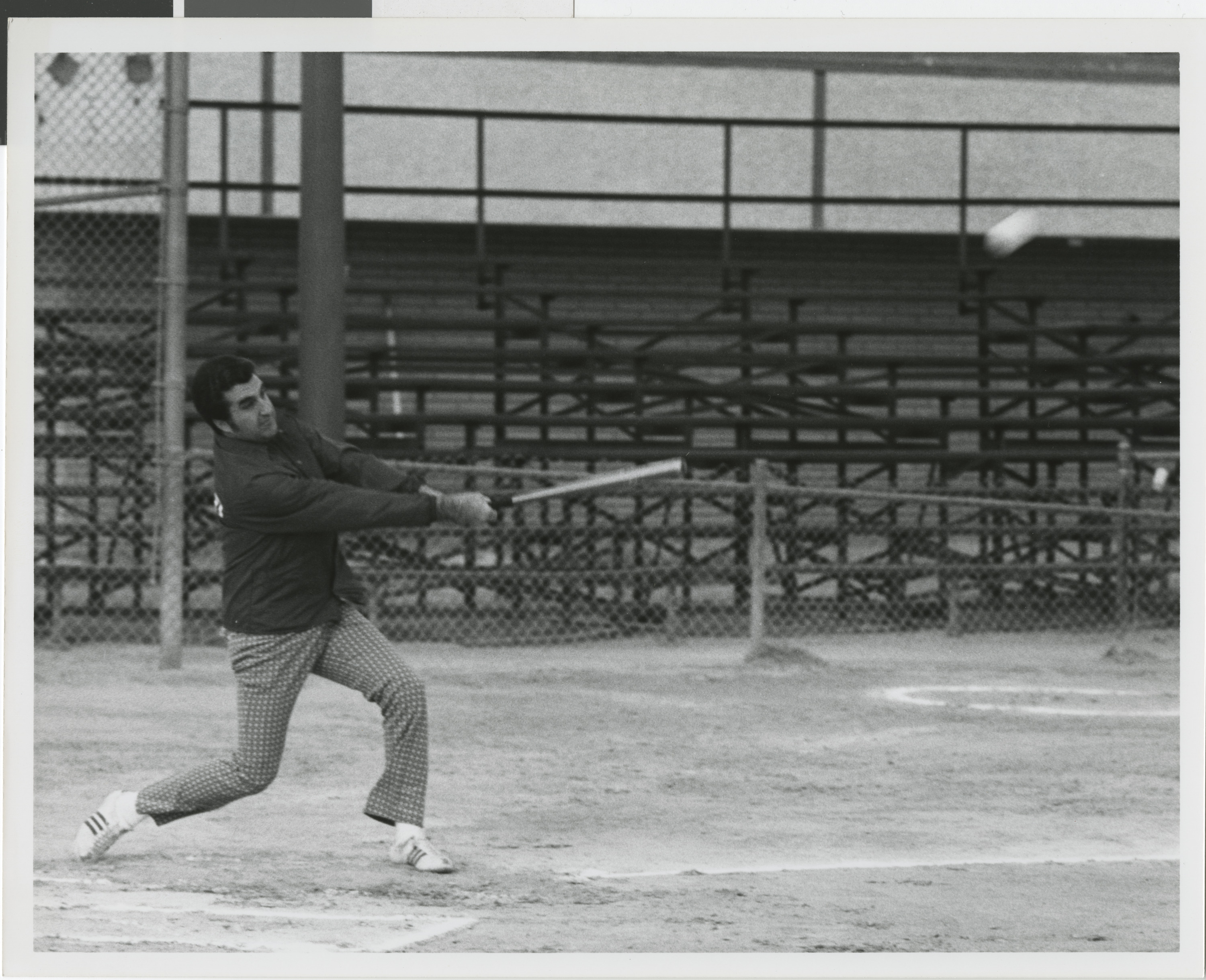 Photograph of Ron Lurie swinging a baseball bat on a baseball field
