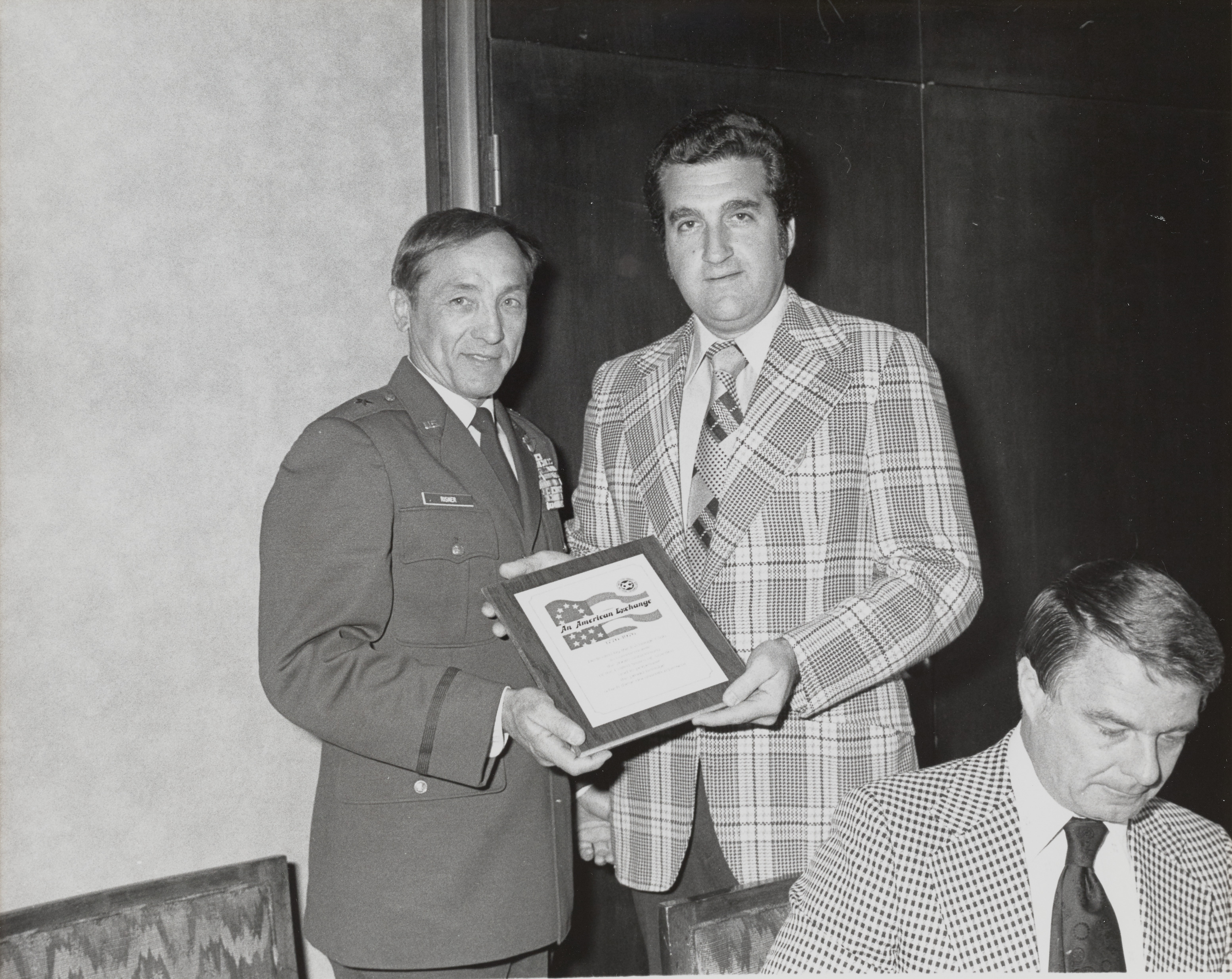 Photograph of Ron Lurie and Mr. Risher holding An American Exchange plaque