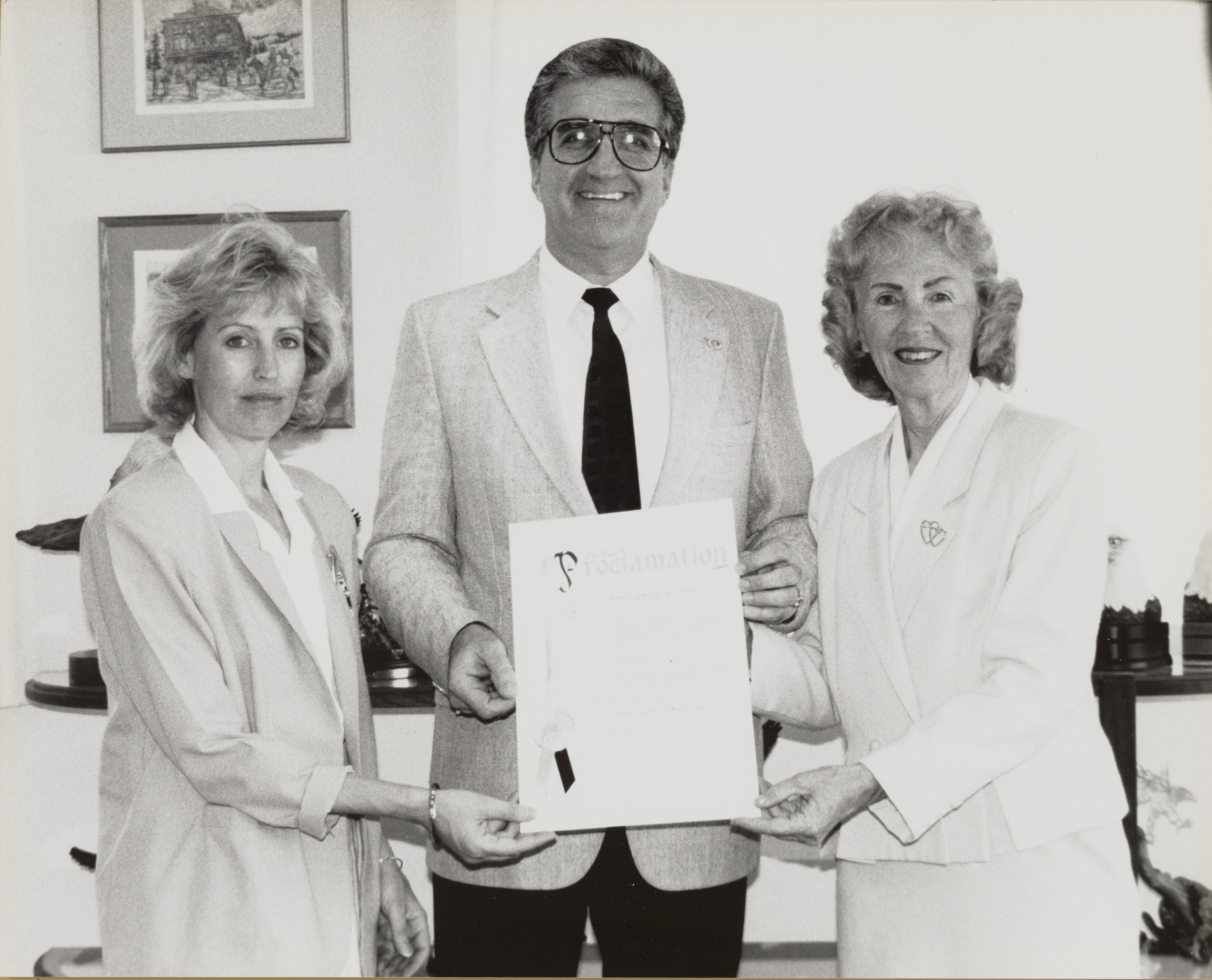 Photograph of Ron Lurie with two women presenting proclamation for National Consumer Credit Month, May 1990