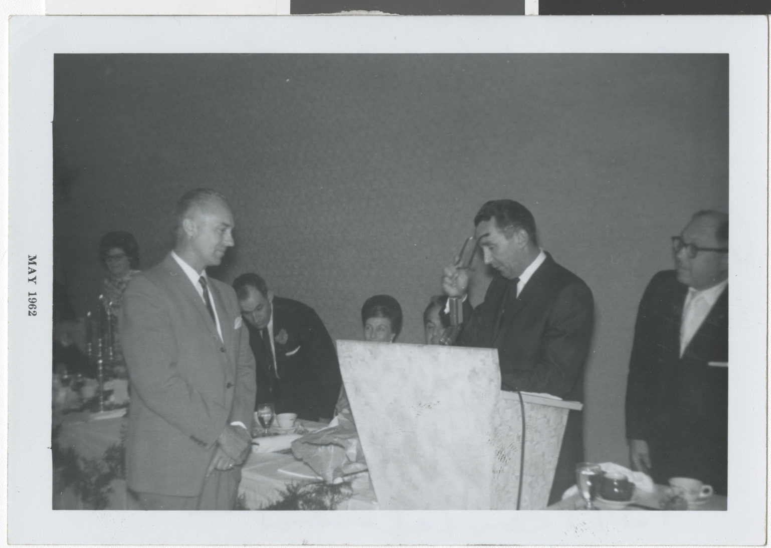 Photograph of Dave Goldwater reading plaque presented to E. Parry Thomas for Man of the Year award, B'nai B'rith installation, May 1962