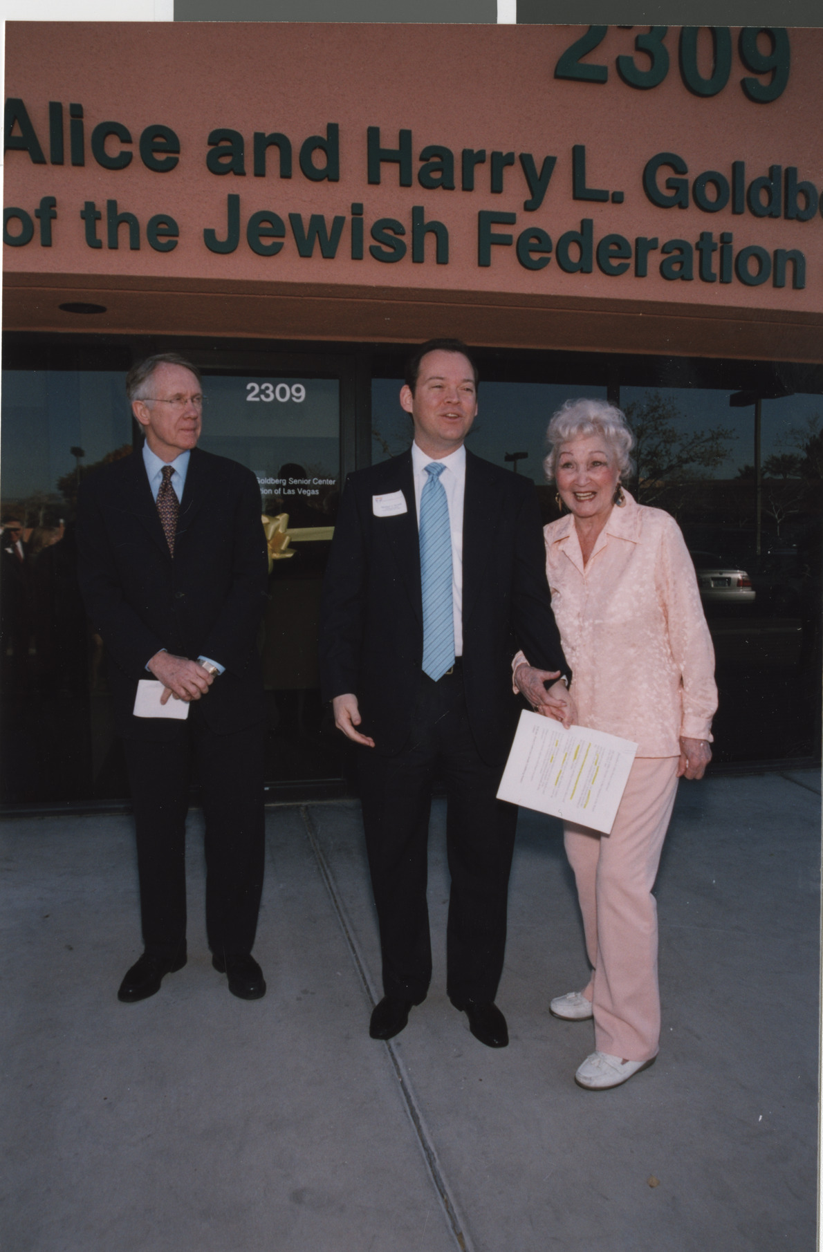 Photograph of Michael Novick with Senator Harry Reid and unidentified woman outside the Alice and Harry L. Goldberg Senior Center
